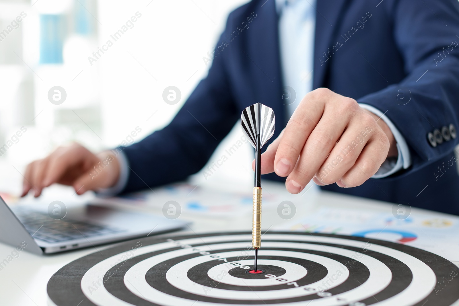 Photo of Man with dart aiming at dartboard while working indoors, closeup