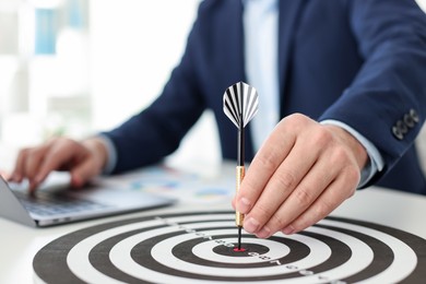 Photo of Man with dart aiming at dartboard while working indoors, closeup