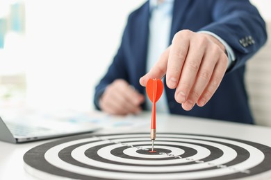 Photo of Man with dart aiming at dartboard while working indoors, closeup