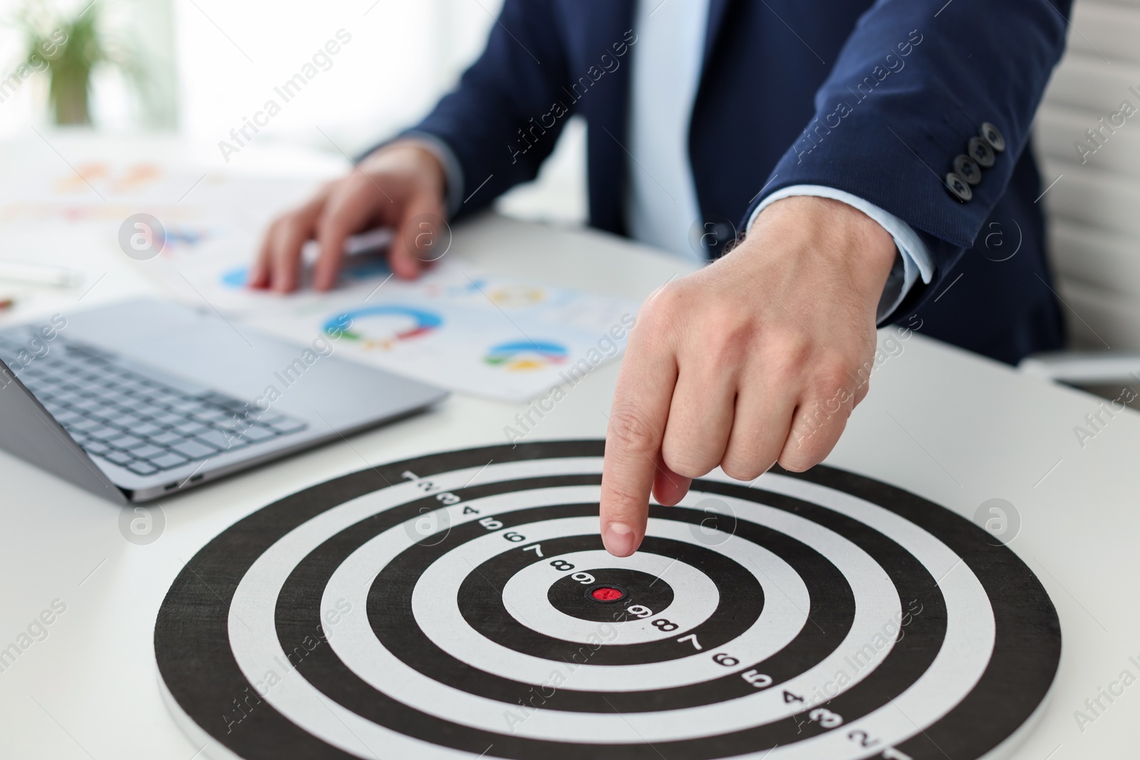 Man pointing at dartboard at white table indoors, closeup Photo of Man pointing at dartboard at white table indoors, closeup