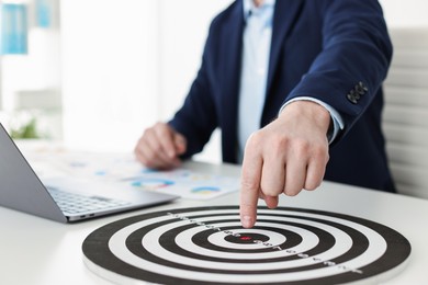 Photo of Man pointing at dartboard at white table indoors, closeup
