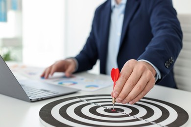 Photo of Man with dart aiming at dartboard while working indoors, closeup