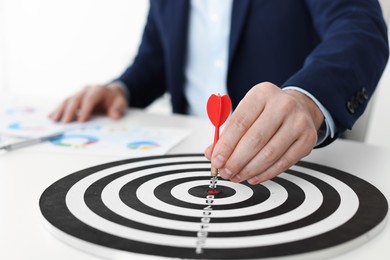 Photo of Man with dart aiming at dartboard while working indoors, closeup