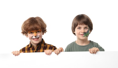 Photo of Cute boys with colorful face paintings and blank banner on white background