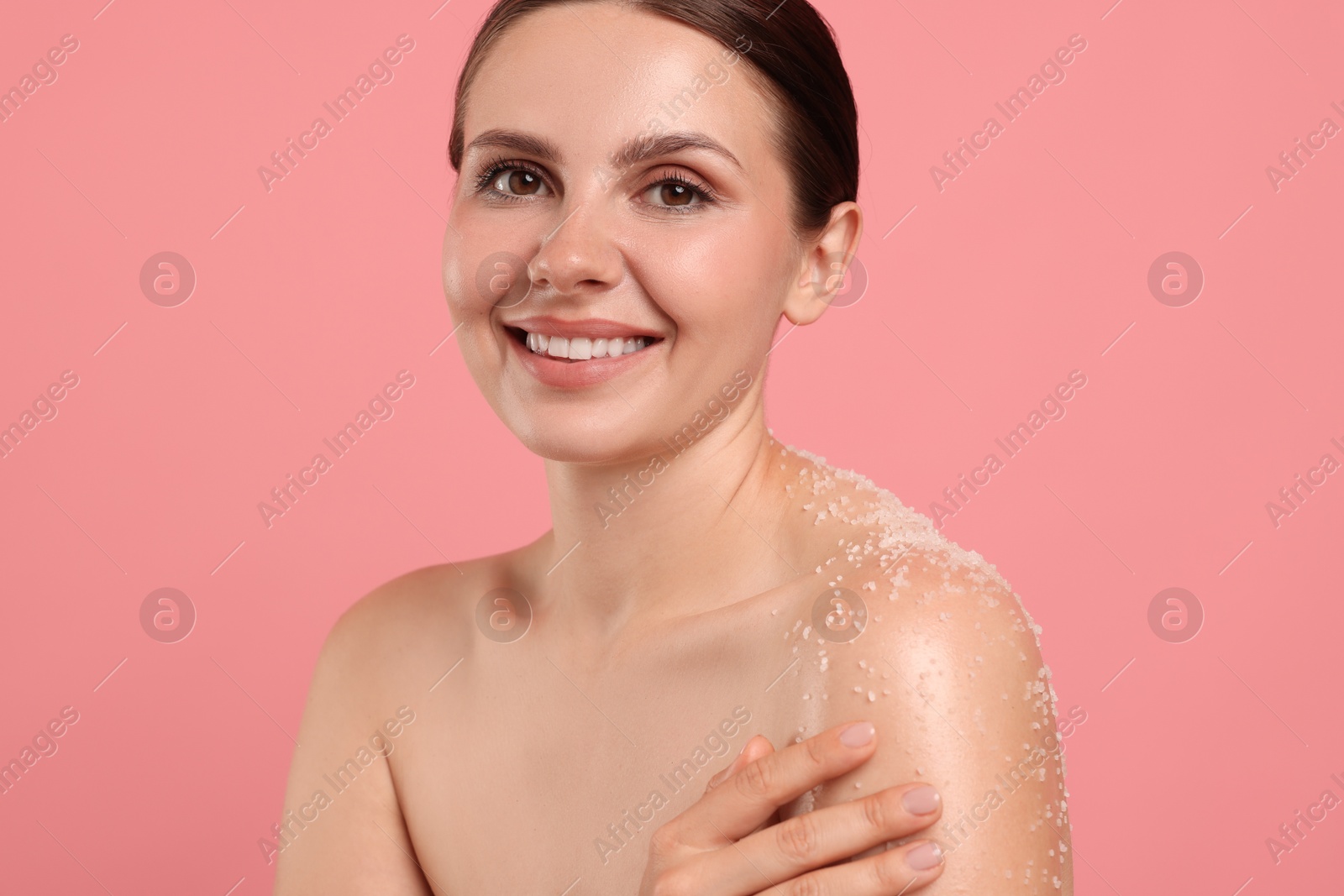 Smiling woman with body scrub on her skin against pink background Photo of Smiling woman with body scrub on her skin against pink background