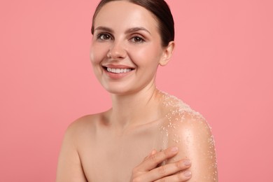 Photo of Smiling woman with body scrub on her skin against pink background