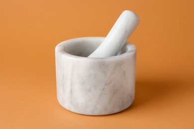 Photo of Marble mortar and pestle on light brown background, closeup