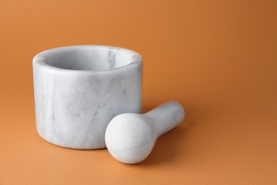 Photo of Marble mortar and pestle on light brown background, closeup. Space for text