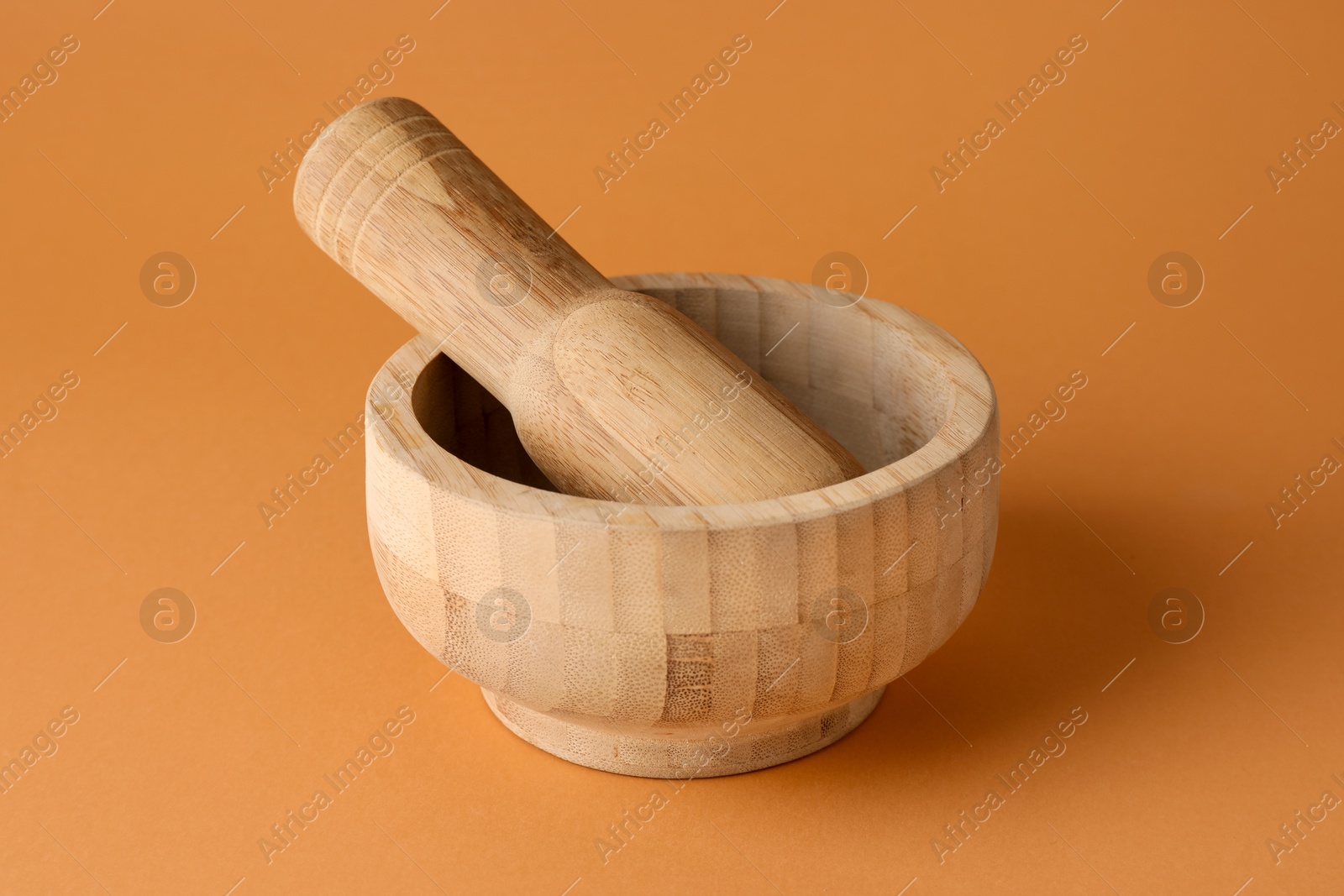 Wooden mortar and pestle on light brown background, closeup Photo of Wooden mortar and pestle on light brown background, closeup