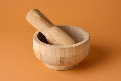 Photo of Wooden mortar and pestle on light brown background, closeup