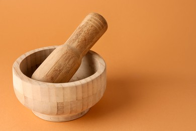 Photo of Wooden mortar and pestle on light brown background, closeup. Space for text