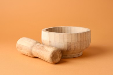Photo of Wooden mortar and pestle on light brown background, closeup