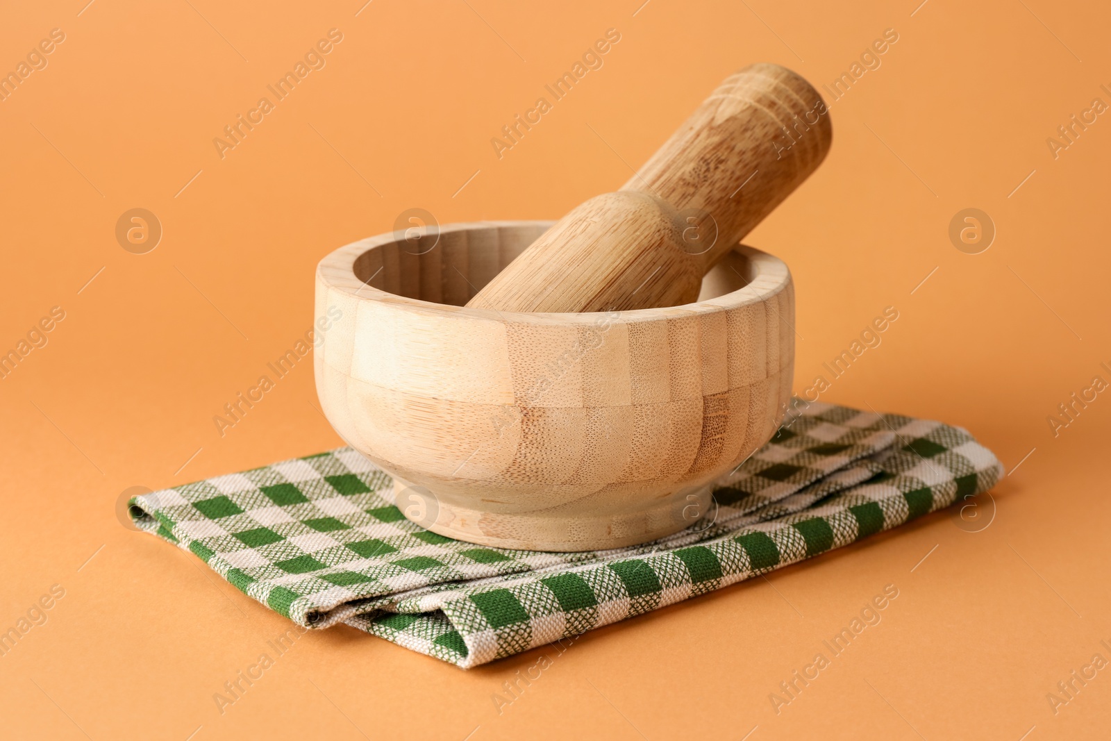 Wooden mortar, pestle and cloth on light brown background, closeup Photo of Wooden mortar, pestle and cloth on light brown background, closeup
