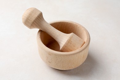 Photo of Wooden mortar and pestle on white table, closeup