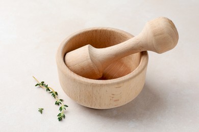 Photo of Wooden mortar, pestle and thyme on white table, closeup