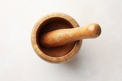 Photo of Wooden mortar and pestle on white table, top view