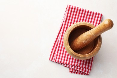 Photo of Wooden mortar, pestle and cloth on white table, top view. Space for text