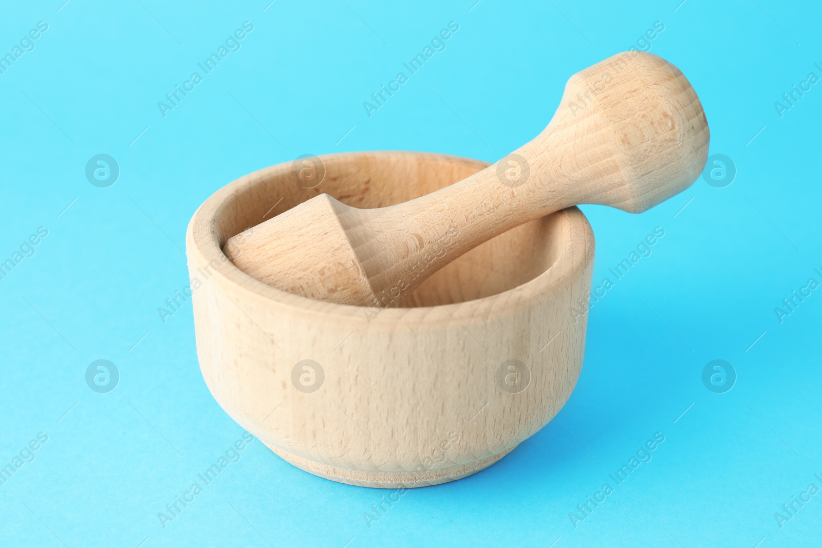 Wooden mortar and pestle on light blue background, closeup Photo of Wooden mortar and pestle on light blue background, closeup