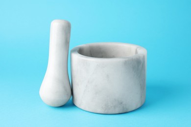 Photo of Marble mortar and pestle on light blue background, closeup