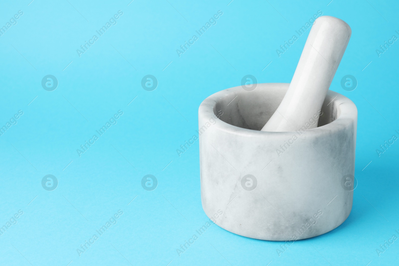 Marble mortar and pestle on light blue background, closeup. Space for text Photo of Marble mortar and pestle on light blue background, closeup. Space for text