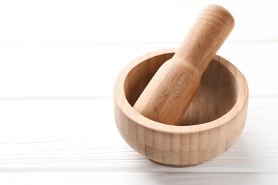 Photo of Mortar and pestle on white wooden table, closeup. Space for text