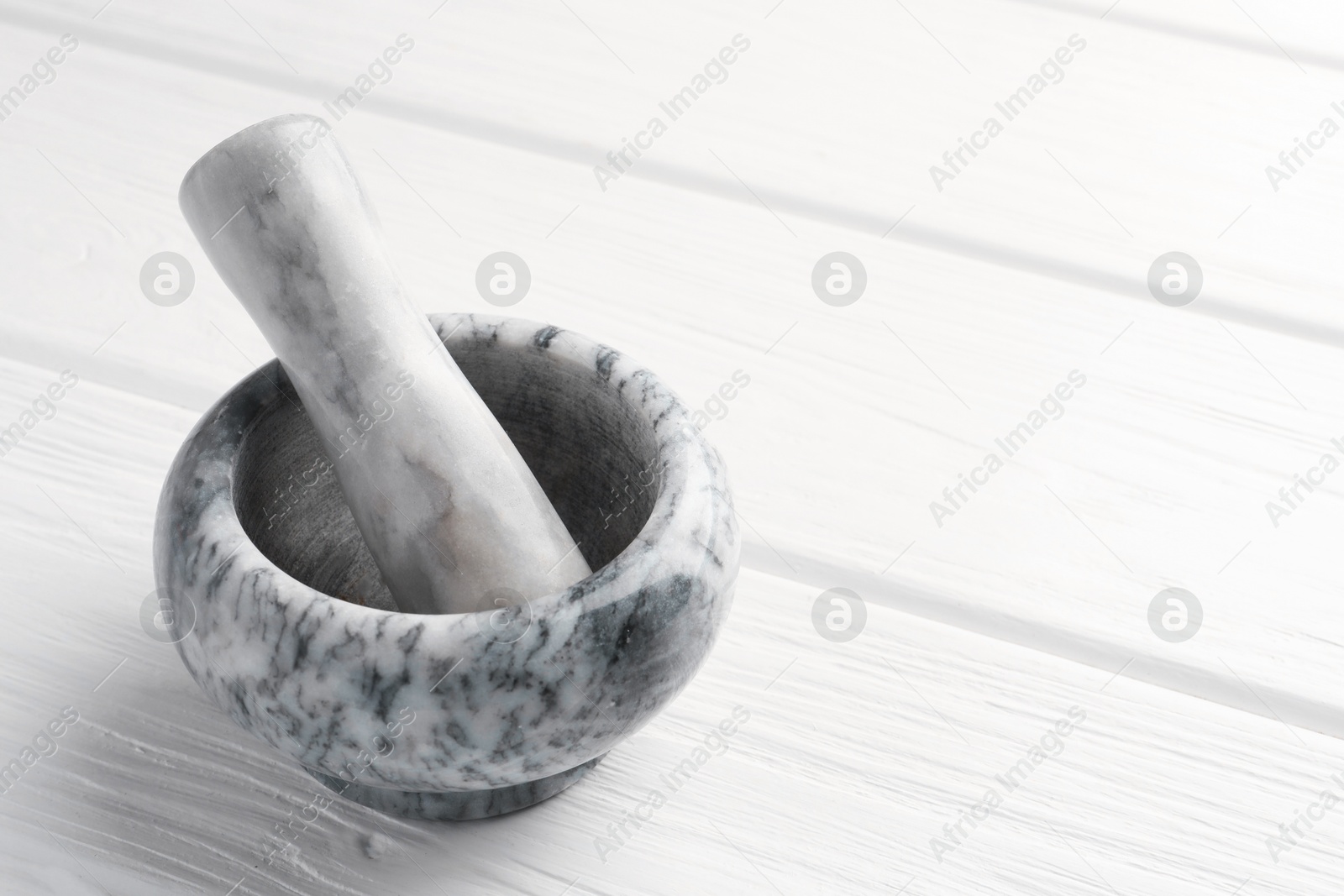 Marble mortar and pestle on white wooden table, closeup. Space for text Photo of Marble mortar and pestle on white wooden table, closeup. Space for text