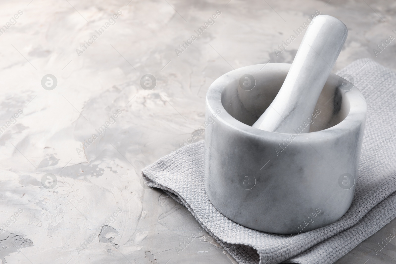 Marble mortar, pestle and cloth on grey textured table, closeup. Space for text Photo of Marble mortar, pestle and cloth on grey textured table, closeup. Space for text