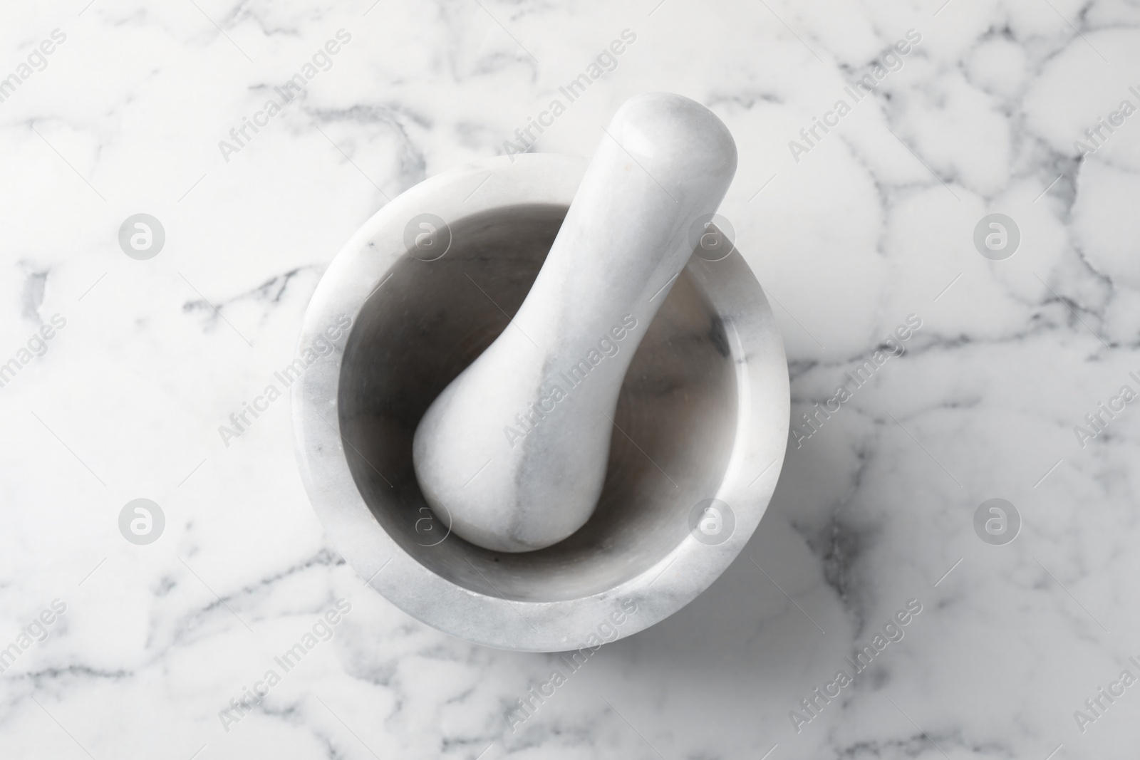 Mortar and pestle on white marble table, top view Photo of Mortar and pestle on white marble table, top view