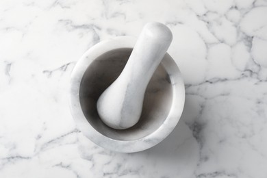 Photo of Mortar and pestle on white marble table, top view