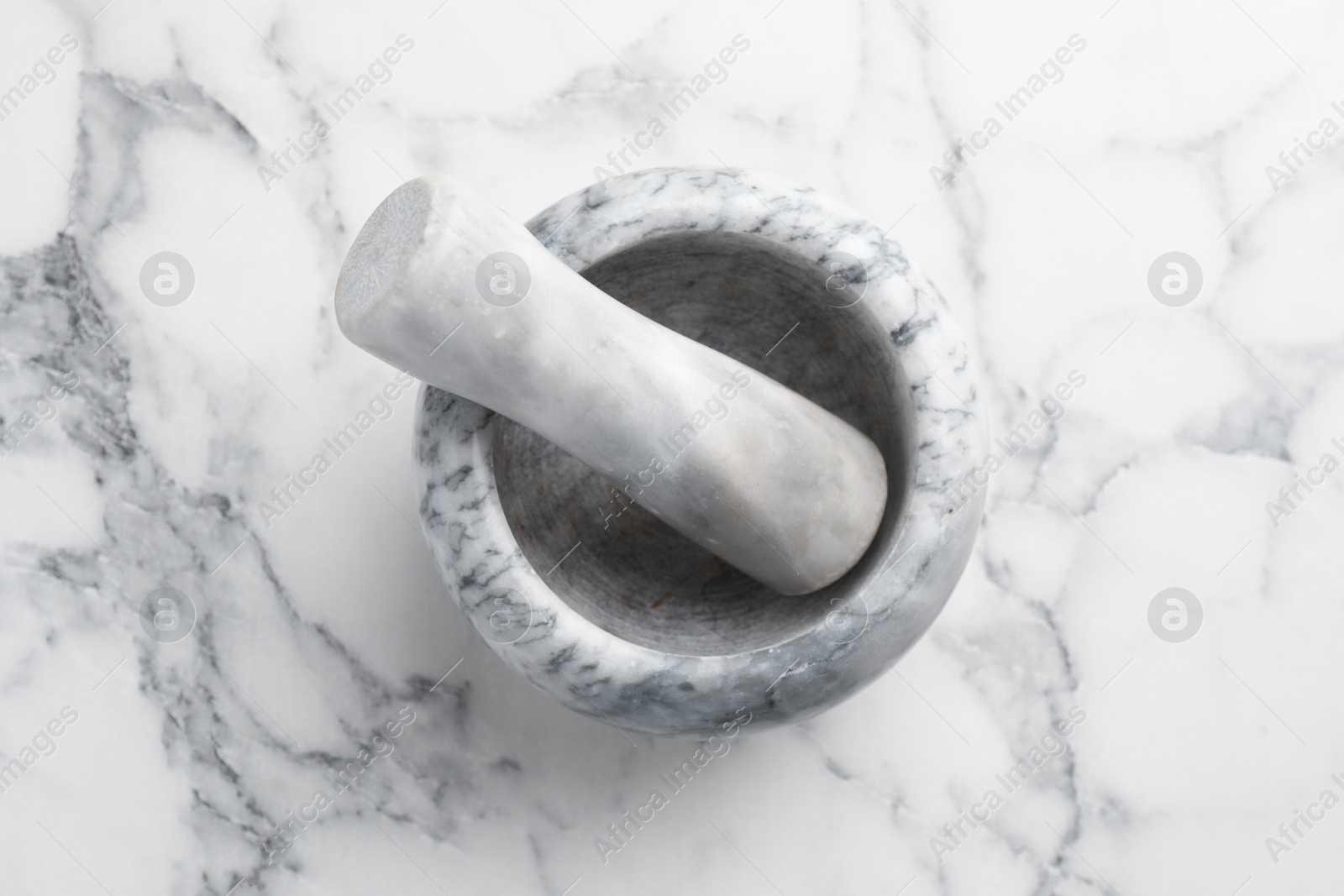 Mortar and pestle on white marble table, top view Photo of Mortar and pestle on white marble table, top view