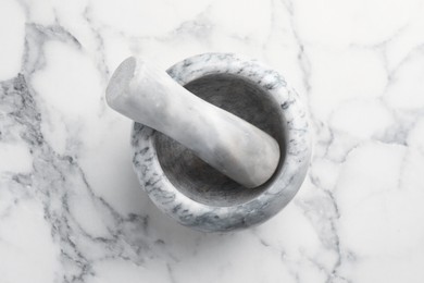 Photo of Mortar and pestle on white marble table, top view