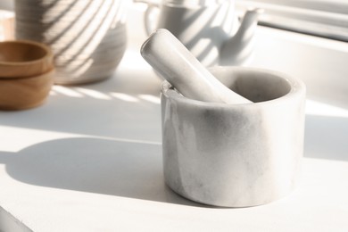 Photo of Marble mortar and pestle on windowsill indoors, closeup. Space for text