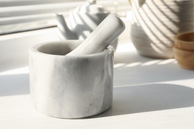 Photo of Marble mortar and pestle on windowsill indoors, closeup. Space for text
