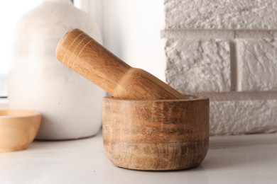Photo of Wooden mortar and pestle on white table indoors, closeup