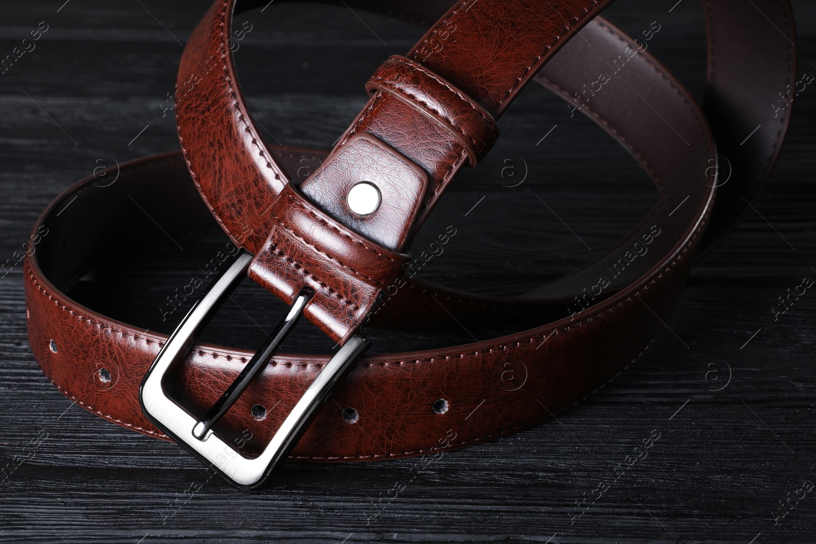 One brown leather belt on black wooden table, closeup Photo of One brown leather belt on black wooden table, closeup