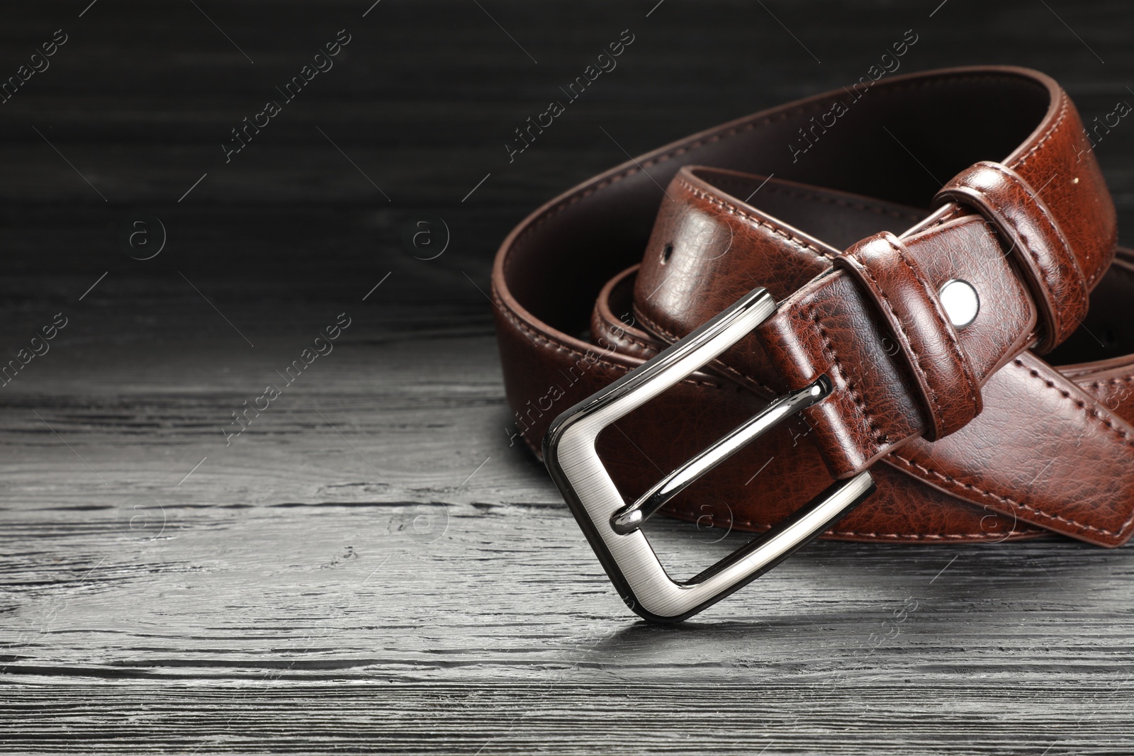 One brown leather belt on wooden table, closeup. Space for text Photo of One brown leather belt on wooden table, closeup. Space for text