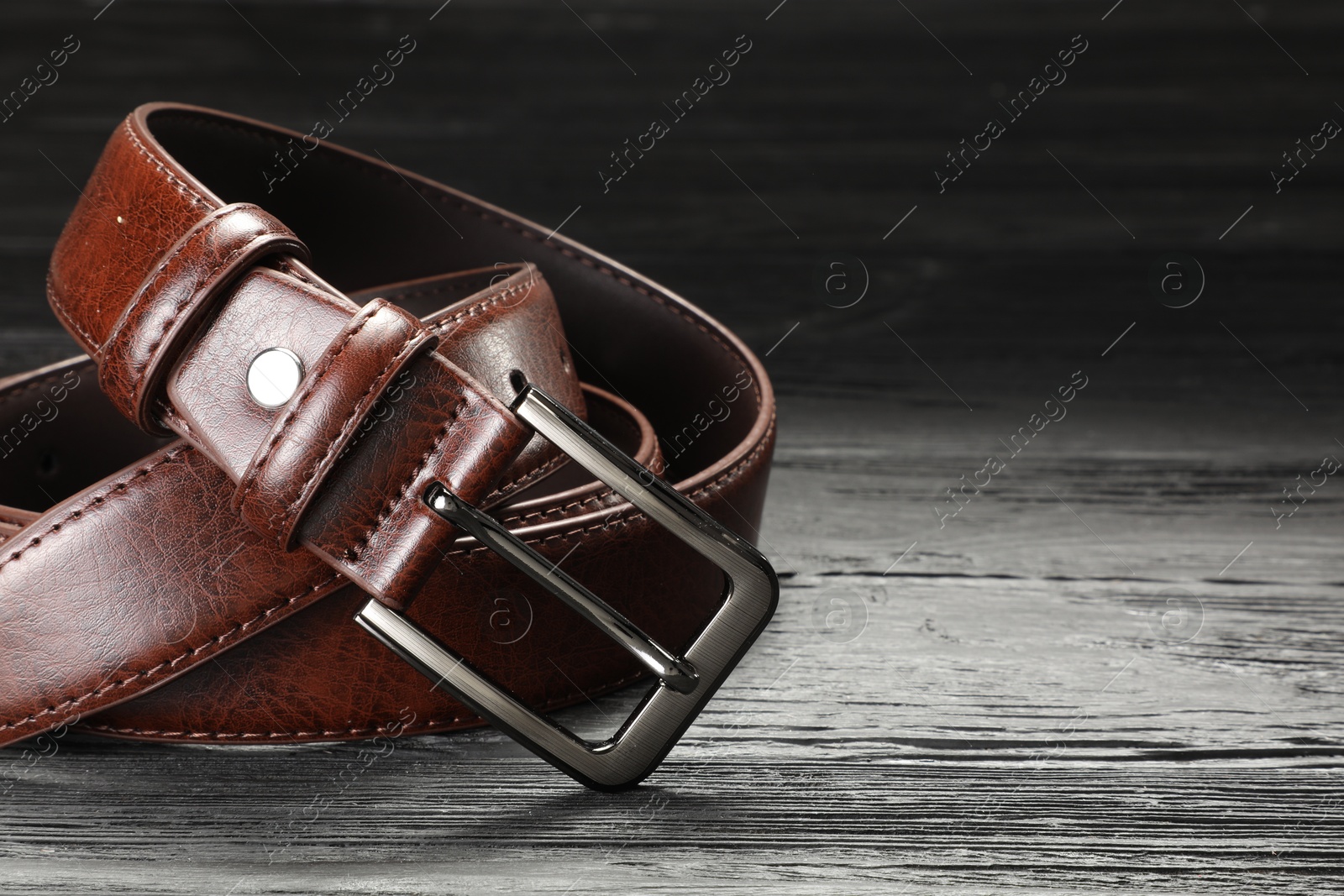 One brown leather belt on wooden table, closeup. Space for text Photo of One brown leather belt on wooden table, closeup. Space for text