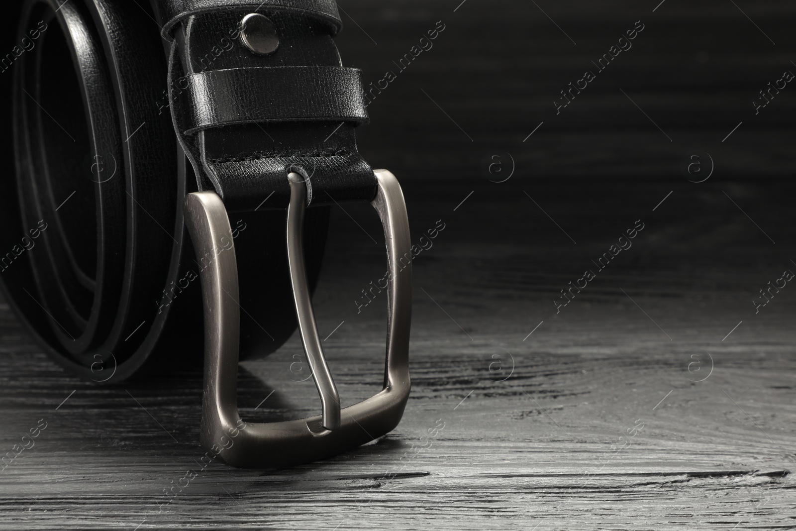 One black leather belt on wooden table, closeup. Space for text Photo of One black leather belt on wooden table, closeup. Space for text