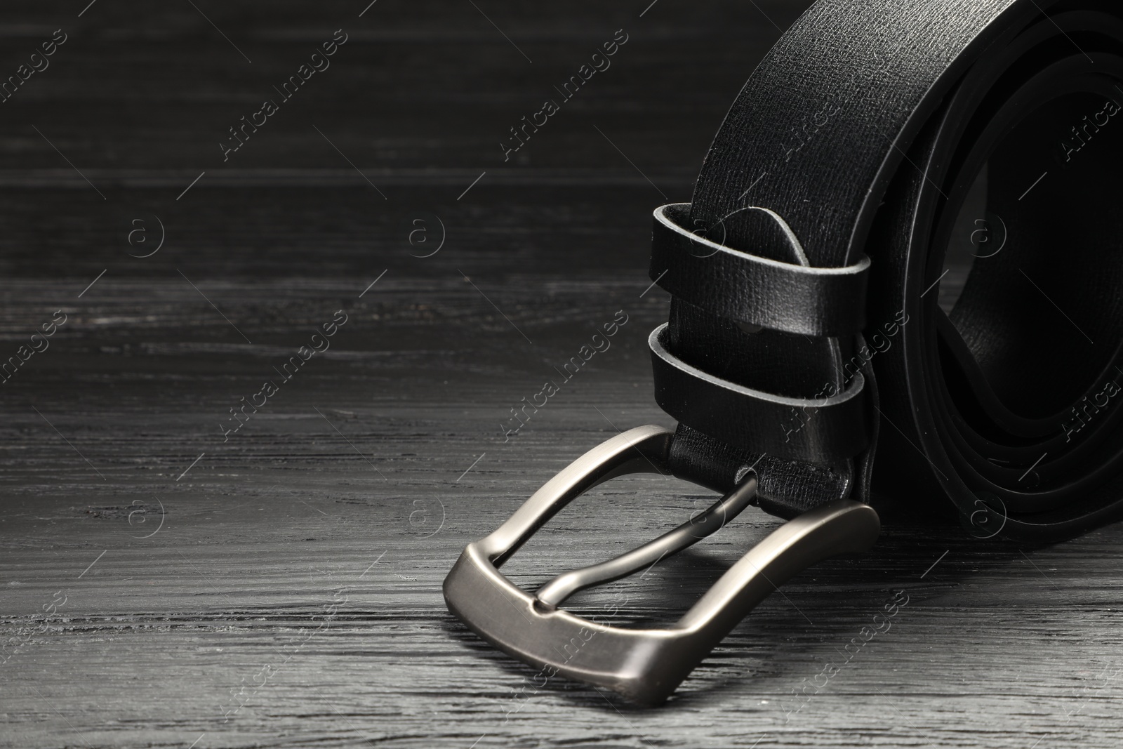 One black leather belt on wooden table, closeup. Space for text Photo of One black leather belt on wooden table, closeup. Space for text
