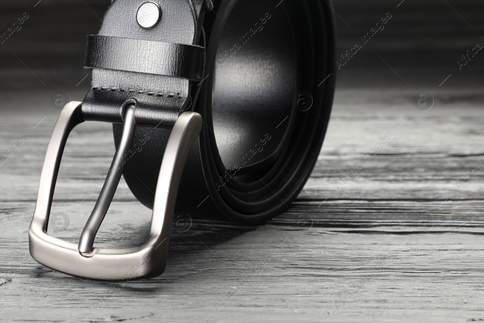 One black leather belt on wooden table, closeup. Space for text Photo of One black leather belt on wooden table, closeup. Space for text