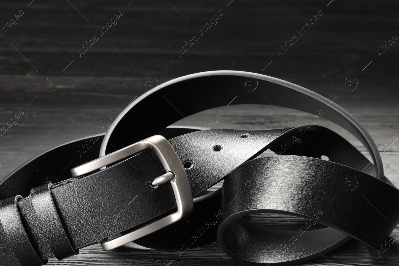 One black leather belt on wooden table, closeup Photo of One black leather belt on wooden table, closeup