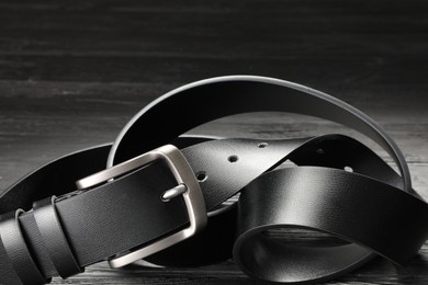 Photo of One black leather belt on wooden table, closeup