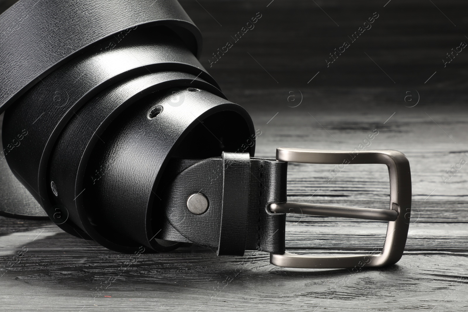 One black leather belt on wooden table, closeup Photo of One black leather belt on wooden table, closeup