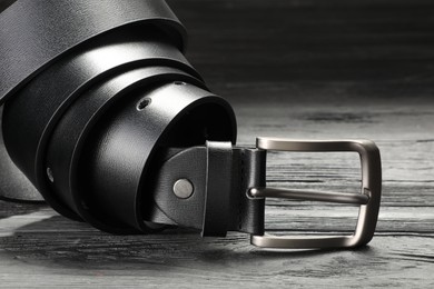 Photo of One black leather belt on wooden table, closeup