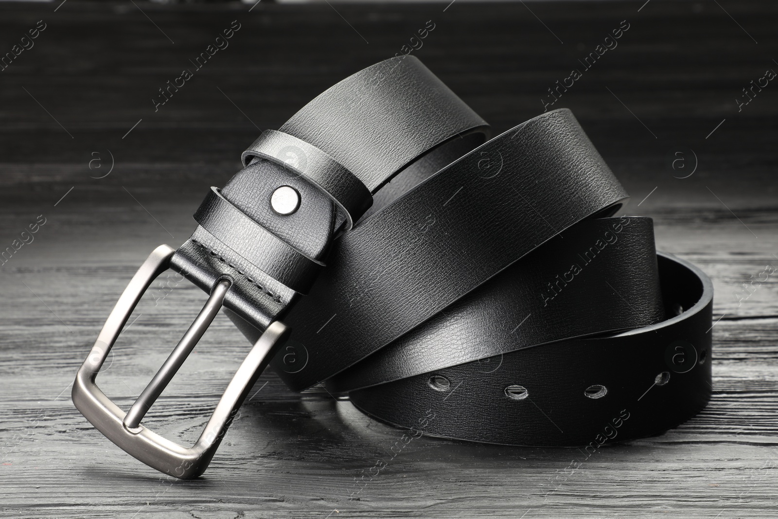 One black leather belt on wooden table, closeup Photo of One black leather belt on wooden table, closeup