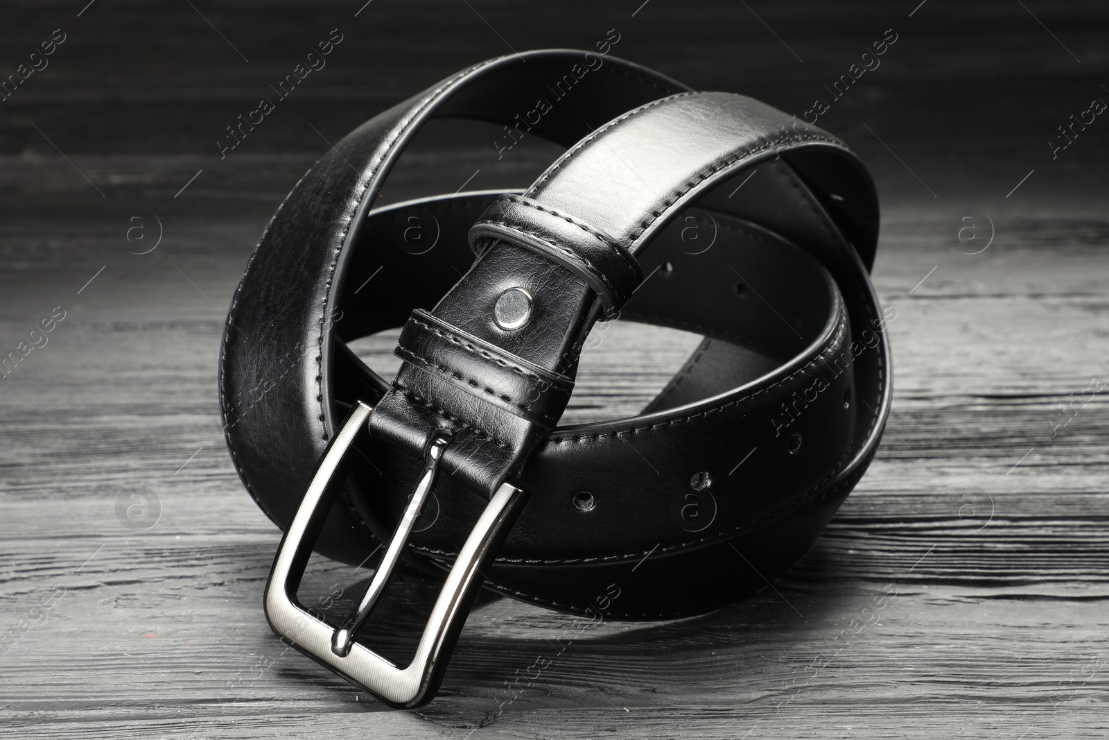 One black leather belt on wooden table, closeup Photo of One black leather belt on wooden table, closeup