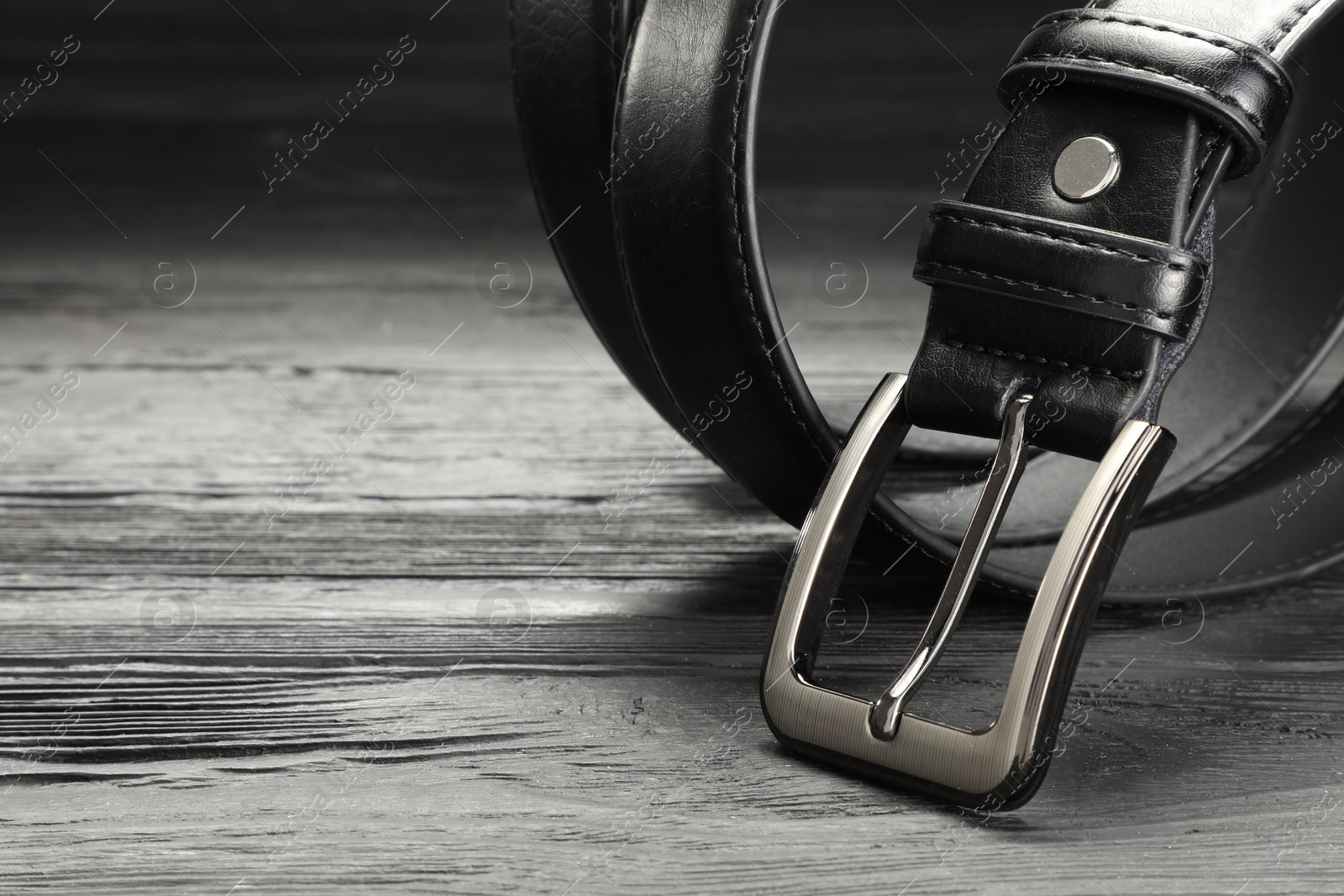 One black leather belt on wooden table, closeup. Space for text Photo of One black leather belt on wooden table, closeup. Space for text