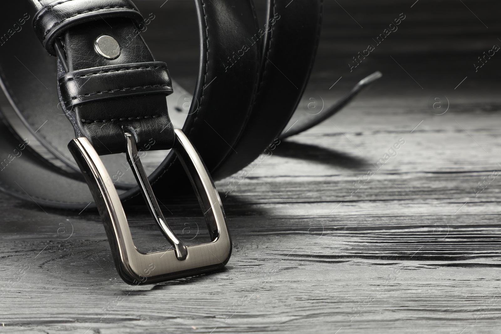 One black leather belt on wooden table, closeup. Space for text Photo of One black leather belt on wooden table, closeup. Space for text