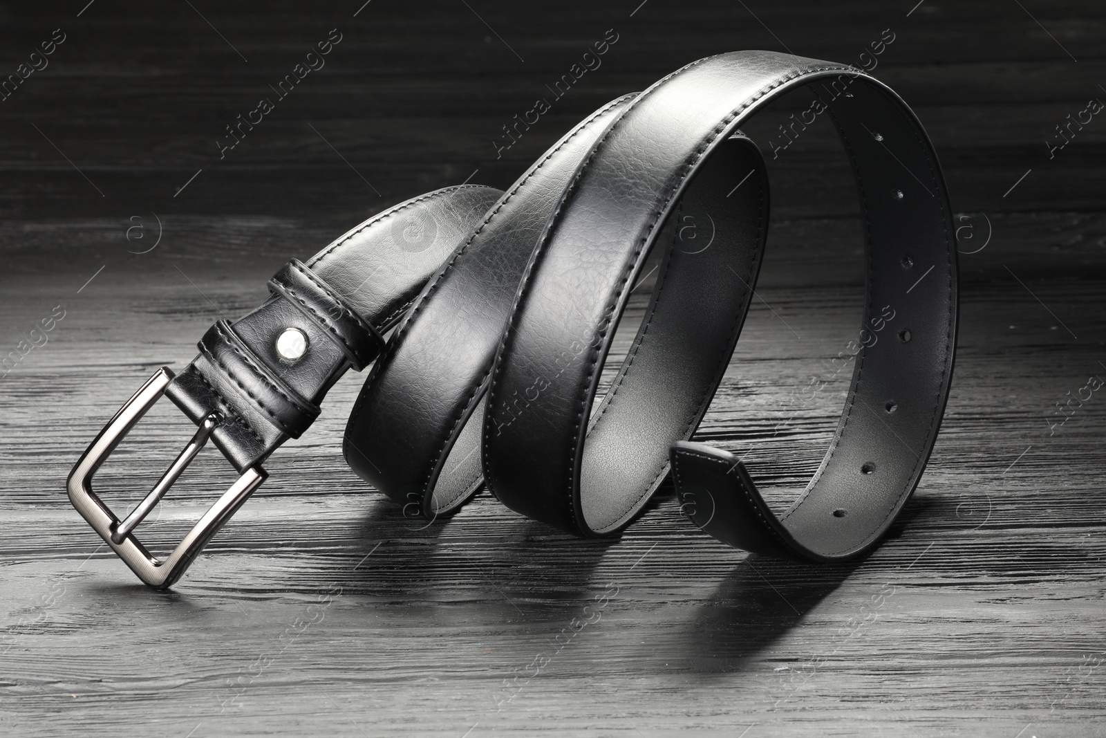 One black leather belt on wooden table, closeup Photo of One black leather belt on wooden table, closeup