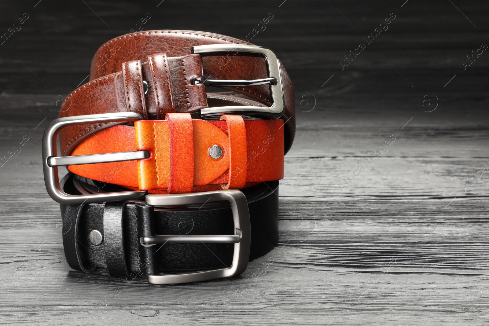 Three leather belts on wooden table, closeup. Space for text Photo of Three leather belts on wooden table, closeup. Space for text